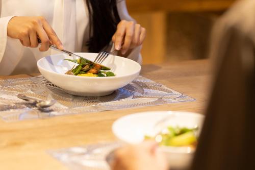 a woman is eating a bowl of food at NIPPONIA HARIMA FUKUSAKI ZOUSHONO YAKATA in Fukusaki