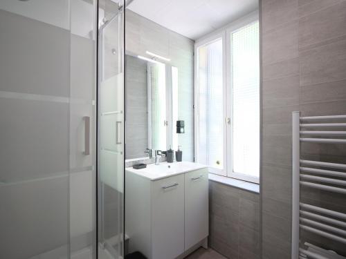 une salle de bain blanche avec un lavabo et une douche dans l'établissement Charmant T2 avec Wifi, proche thermes à La Bourboule - FR-1-608-272, à La Bourboule