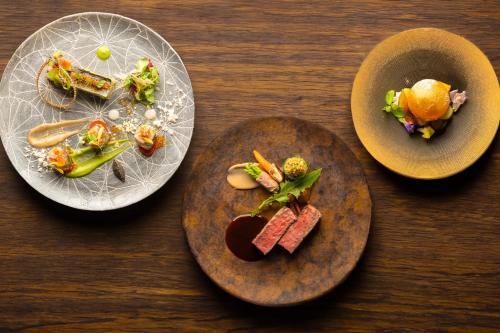 three plates of food on a wooden table at NIPPONIA HARIMA FUKUSAKI ZOUSHONO YAKATA in Fukusaki