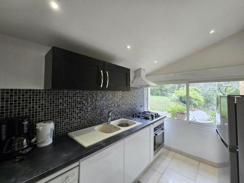 une cuisine avec des armoires blanches, un évier et une fenêtre dans l'établissement Maison familiale avec grand jardin, proche de Sarlat, cheminée, Wifi, animaux acceptés - FR-1-616-61, à Sainte-Mondane