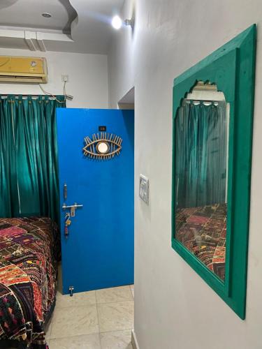 a bedroom with a blue door and a mirror at Blue Eye Hostel in Jaisalmer