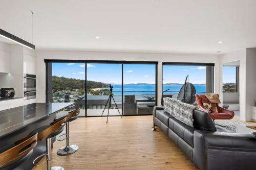 a living room with a couch and a view of the ocean at Beachside Luxury Villa - Expansive Panoramic Vistas in Kingston Beach