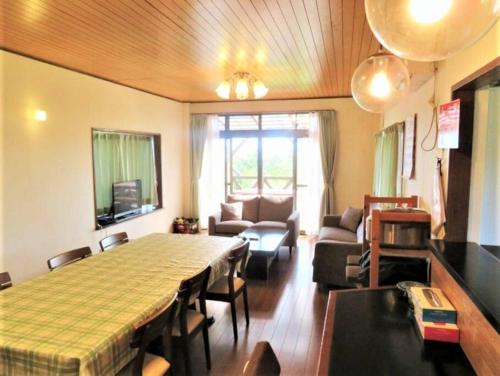 a living room with a large table and a living room with chairs at 熱海温泉自然郷の眺望の貸し切り in Atami