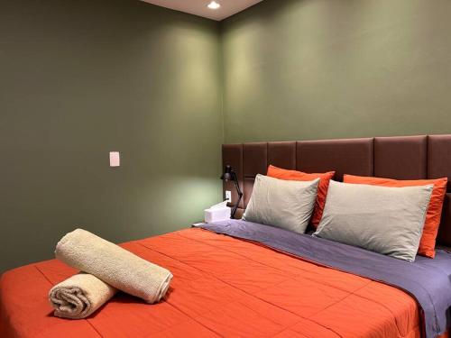 a bedroom with a bed with an orange blanket at Linda cobertura no Vila da Serra in Nova Lima