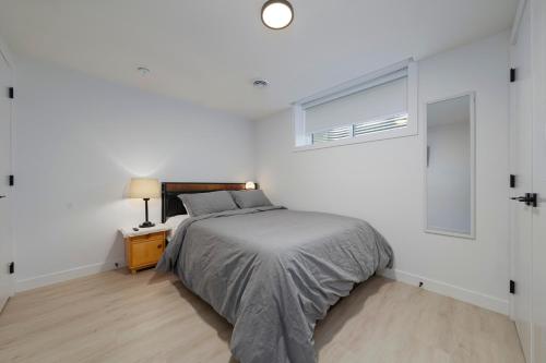 a white bedroom with a bed and a window at Modern Suite by Royal Alexandra Hospital l Free Parking WiFi Netflix in Edmonton