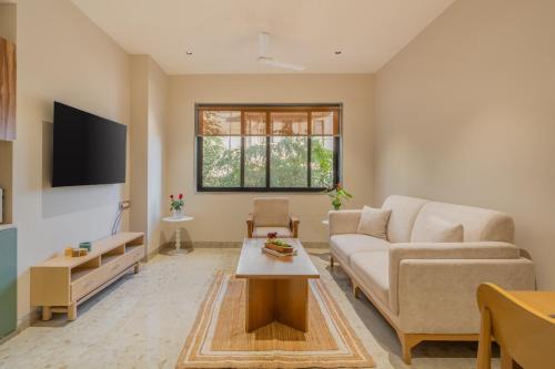 a living room with a couch and a table at ELIVAAS 1 BHK with Rooftop Pool - Kamerios Verano in Goa