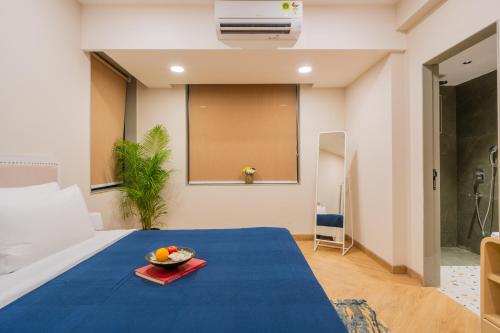 a room with a bed with a bowl of fruit on a table at ELIVAAS 1 BHK with Rooftop Pool - Kamerios Verano in Goa