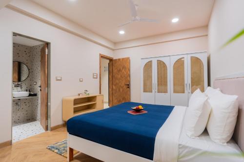 a bedroom with a blue and white bed and a bathroom at ELIVAAS 1 BHK with Rooftop Pool - Kamerios Verano in Goa