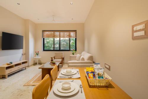 a living room with a table and a couch at ELIVAAS 1 BHK with Rooftop Pool - Kamerios Verano in Goa