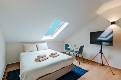 a bedroom with a bed and a tv and a table at Lovely studio fully equipped near subway N11 - Shared bathroom with another Studio in Lisbon