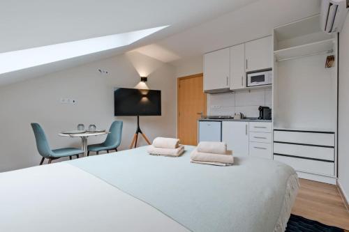 a white bedroom with a large bed and a kitchen at Lovely studio fully equipped near subway N11 - Shared bathroom with another Studio in Lisbon