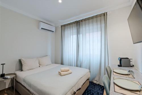 a bedroom with a white bed with two chairs at Lovely studio fully equipped near subway N5 in Lisbon