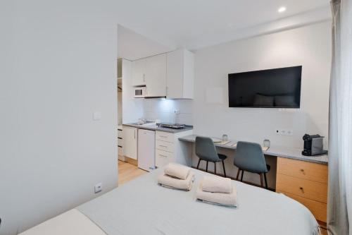 a white kitchen with two chairs and a table at Lovely studio fully equipped near subway N4 in Lisbon