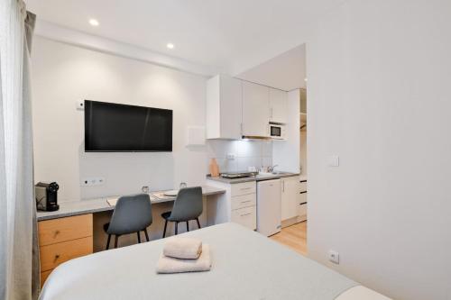 a white kitchen with a table and two chairs at Lovely studio fully equipped near subway N3 in Lisbon