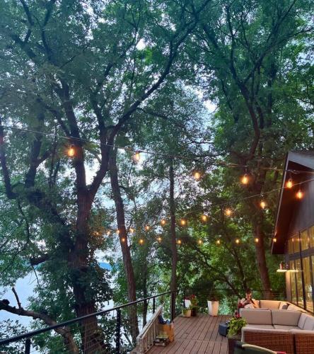 a deck with a bunch of trees with lights at Modern Home with private beach on St. Croix River in Lakeland