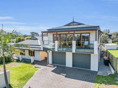 a home with a large deck and a house at Heart Of Long Point in Merimbula