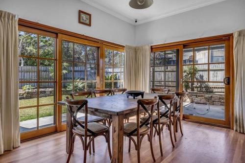 a dining room with a wooden table and chairs at Heart Of Long Point in Merimbula