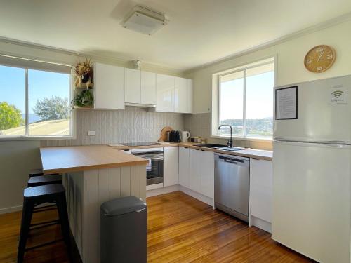 a kitchen with white appliances and a clock on the wall at Quarry House - Bright and Renovated! in Hobart