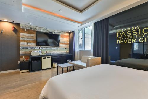 a hotel room with a bed and a flat screen tv at Moonbay Hotel in Busan