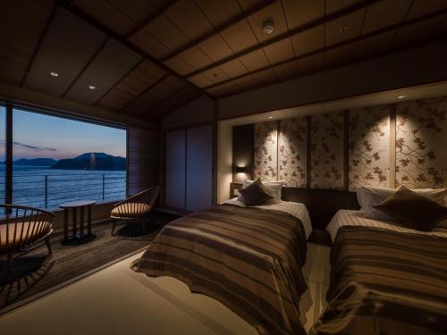 a bedroom with two beds and a view of the water at Inatori Ginsuiso in Higashiizu