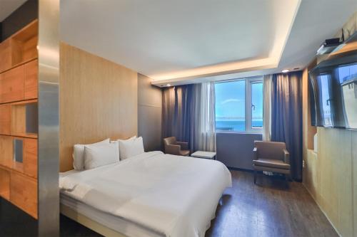 a hotel room with a bed and a large window at Moonbay Hotel in Busan