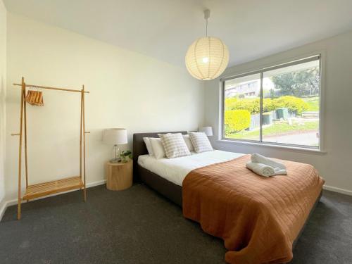 a bedroom with a bed and a large window at Quarry House - Bright and Renovated! in Hobart