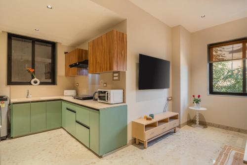 a kitchen with green cabinets and a microwave at ELIVAAS 1 BHK with Jacuzzi & Lift - Kamerios Brisa in Goa