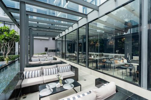a restaurant with glass walls and white couches and tables at Arden Hotel and Residence by At Mind in Pattaya Central