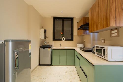 a kitchen with green cabinets and a refrigerator at ELIVAAS 1 BHK with Jacuzzi & Lift - Kamerios Brisa in Goa