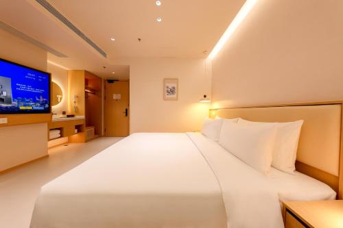 a large white bed in a hotel room with a tv at Mienbias Hotel Shenzhen in Shenzhen