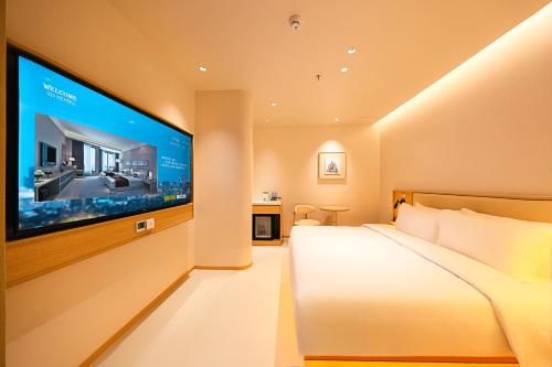 a bedroom with a large flat screen tv on a wall at Mienbias Hotel Shenzhen in Shenzhen