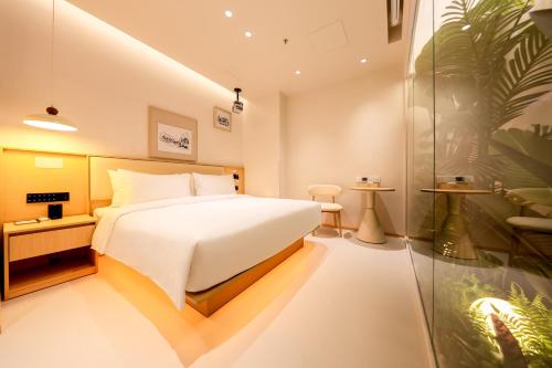a bedroom with a white bed and a glass wall at Mienbias Hotel Shenzhen in Shenzhen