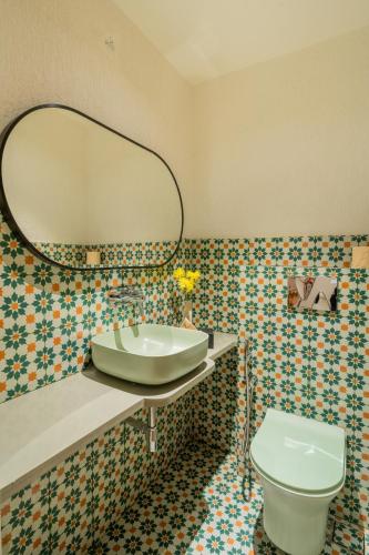 a bathroom with a sink and a toilet and a mirror at ELIVAAS 1 BHK with Jacuzzi & Lift - Kamerios Brisa in Goa