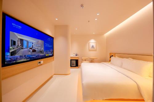 a bedroom with a large flat screen tv on the wall at Mienbias Hotel Shenzhen in Shenzhen