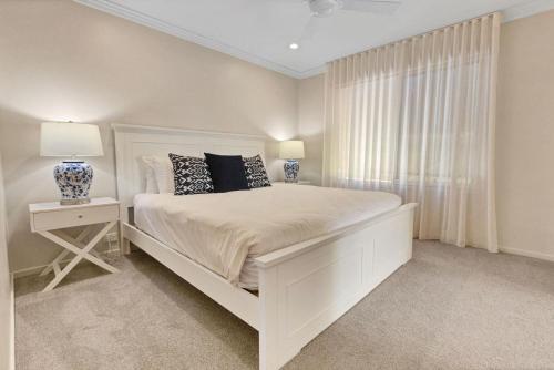 a white bedroom with a white bed and a window at Driftwood @ McMillans in Metung