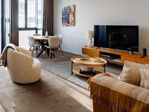 a living room with a couch and a tv and a table at Pavilions Marina Apartment 104 - Wynyard Quarter Viaduct Harbour in Auckland