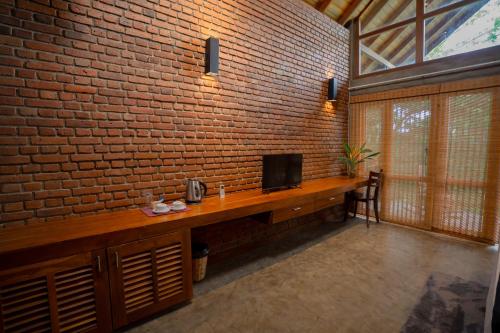 a brick wall with a desk with a television on it at Eliyanth Udawalawe in Udawalawe