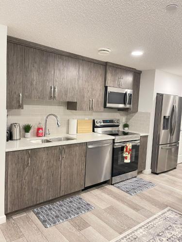 a kitchen with wooden cabinets and stainless steel appliances at Exquisite Basement Suite, 7mins away to Landmark Cinema and Malls in Calgary