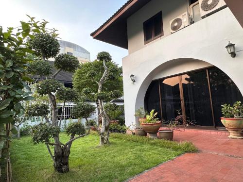 a building with a courtyard with trees and potted plants at Newly-renovated Modern Private Thai Villa with Swimming Pool in Ban Khlong Samrong