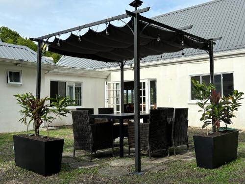 a table and chairs under a black umbrella at Beachwalk Becune in Cap Estate
