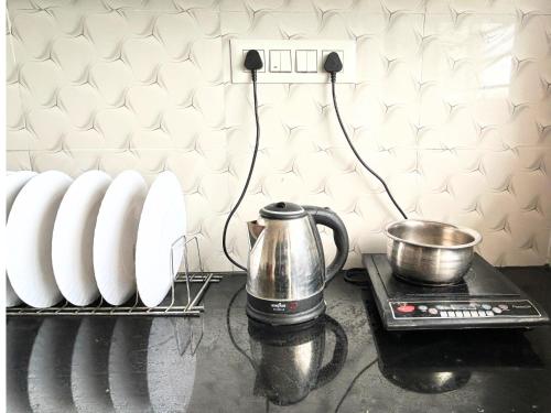 a kitchen counter with a tea kettle and white vases at Mannat Inn Classic Premium - 3BHK in Mysore