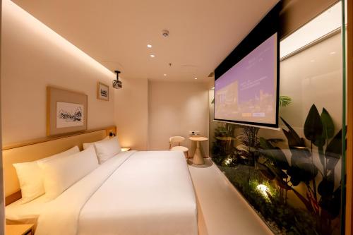 a bedroom with a large white bed and a flat screen tv at Mienbias Hotel Shenzhen in Shenzhen