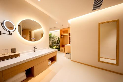 a bathroom with a large mirror and a sink at Mienbias Hotel Shenzhen in Shenzhen