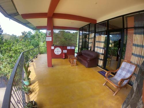a balcony of a house with a couch and chair at Beyond Nomad Luxury Hostel in Ella