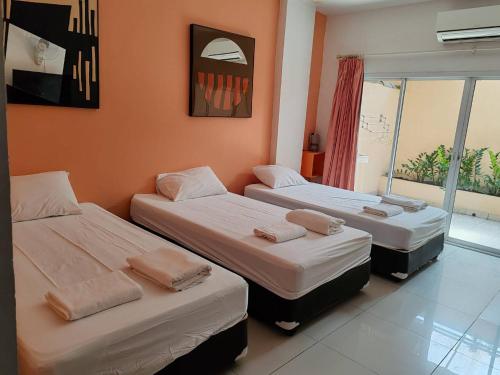 a room with three beds and a window at Jomtien Hostel in Jomtien Beach