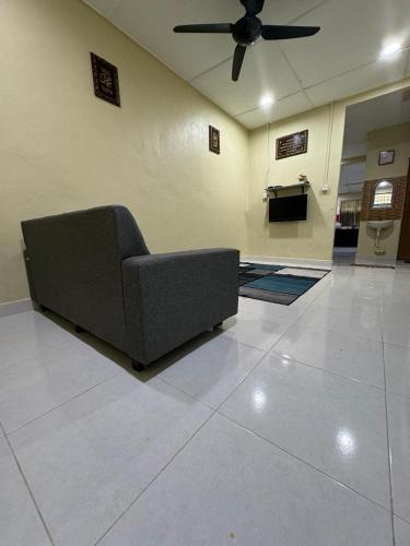 a couch in a living room with a ceiling fan at Homestay Ahmad & Siti in Tanah Merah