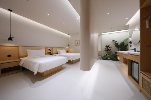 two beds in a hotel room with a bathroom at Mienbias Hotel Shenzhen in Shenzhen