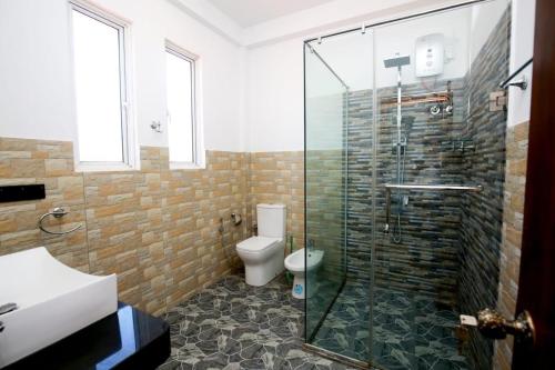 a bathroom with a toilet and a glass shower at Villa Mathe in Dickwella