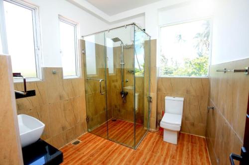 a bathroom with a shower and a toilet and a sink at Villa Mathe in Dickwella