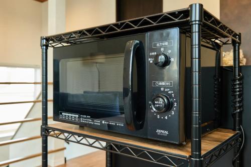 a black microwave on a black stand on a shelf at VILLA Naebo Sapporo Beer Park Hocance in Sapporo